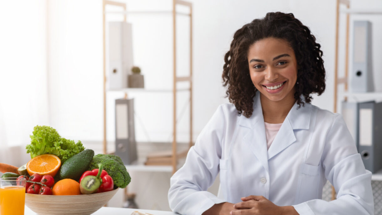 Image d'une diététiste à côté d'un bol de fruits et de légumes