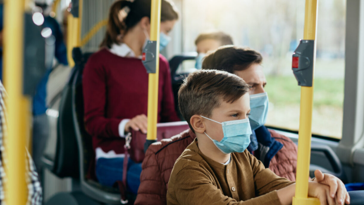 Un garçon qui porte un masque de procédure dans un autobus public.