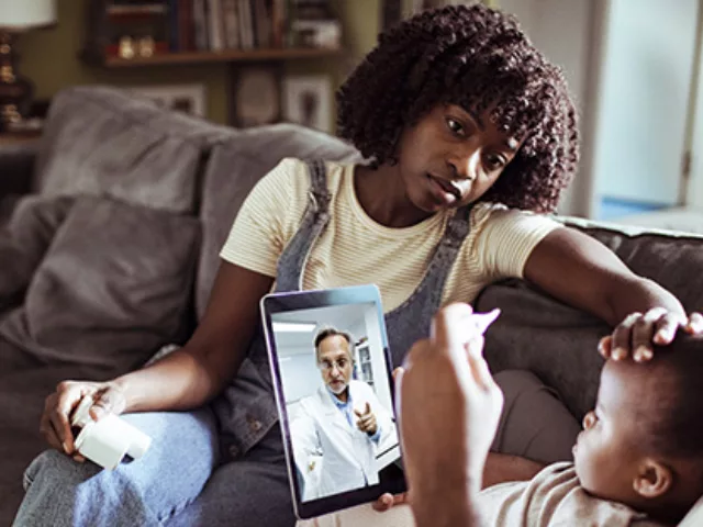Une famille parle à un médecin en téléconsultation avec une tablette